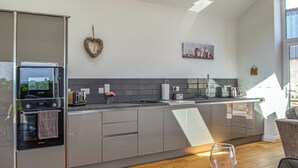Une cuisine moderne dotée d’un four encastré, d’une décoration en forme de cœur et d’une fenêtre laissant entrer la lumière naturelle.
