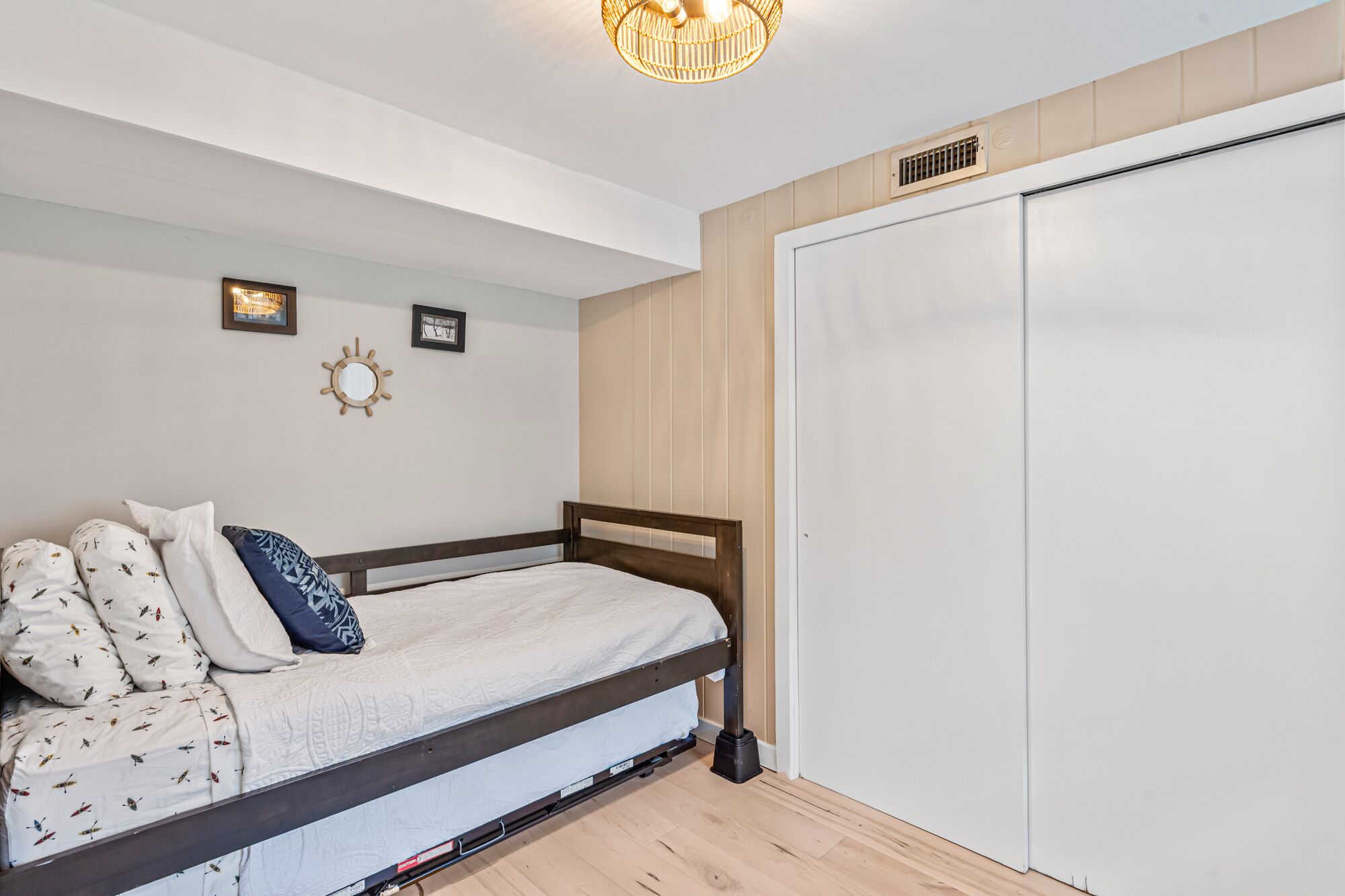 A bedroom with a bed, a wardrobe, and a wall-mounted mirror.