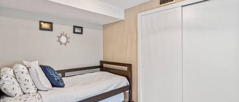 A bedroom with a bed, a wardrobe, and a wall-mounted mirror.