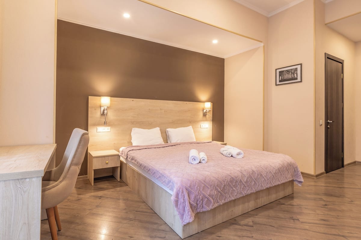 A bedroom with a bed, bedside tables, a chair, and a door.