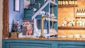 Una zona de bar con grifo, estantes llenos de botellas y un cartel.