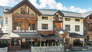 Un hotel con fachada de madera, balcones y zonas de estar al aire libre.