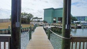 Un muelle de madera que conduce a un embarcadero con un edificio al fondo.