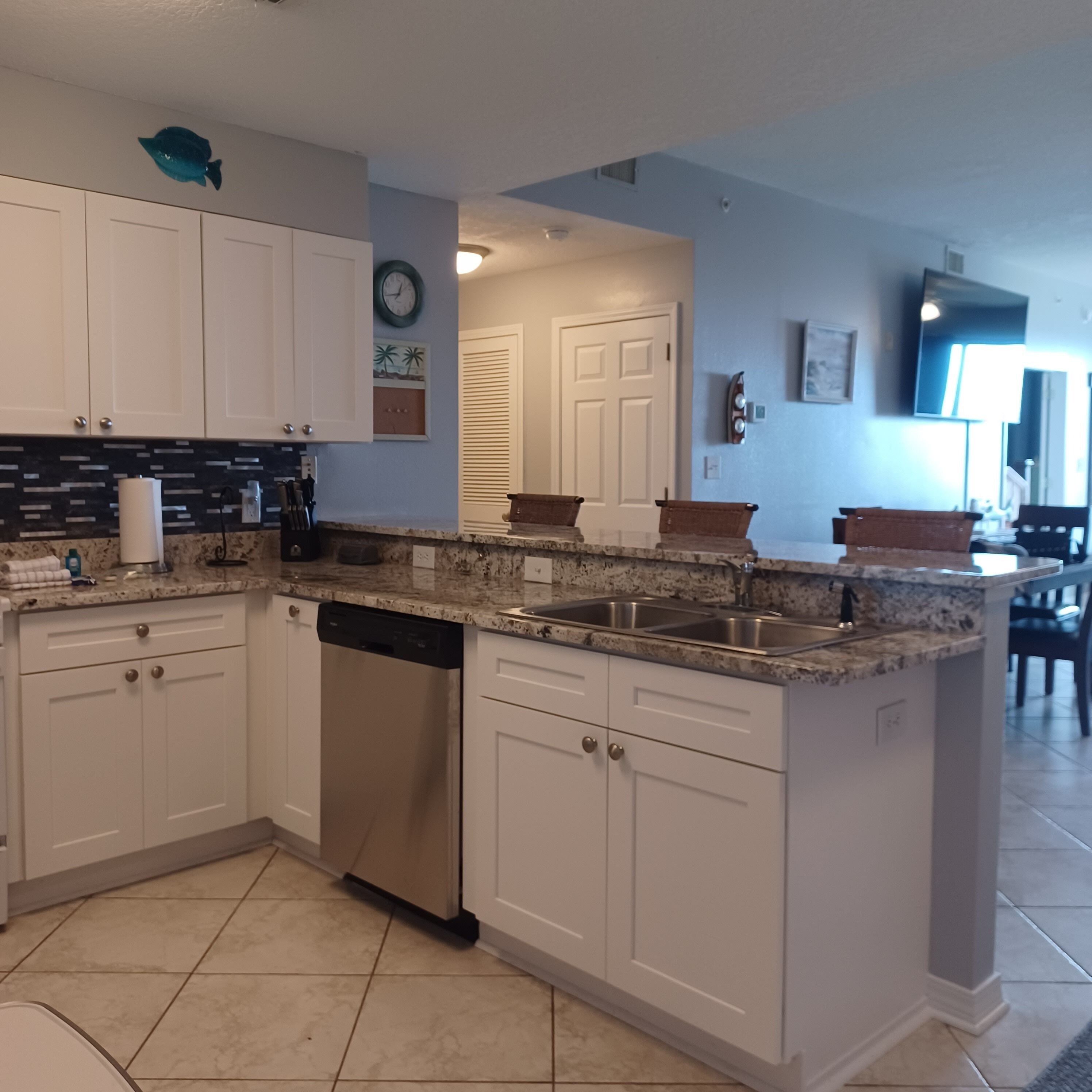 A kitchen with white cabinets, a dishwasher, granite countertops, and a sink.