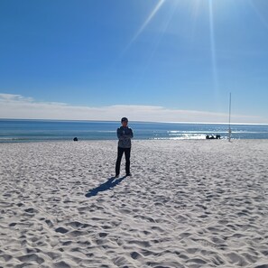 Uma praia de areia com uma pessoa parada no meio.