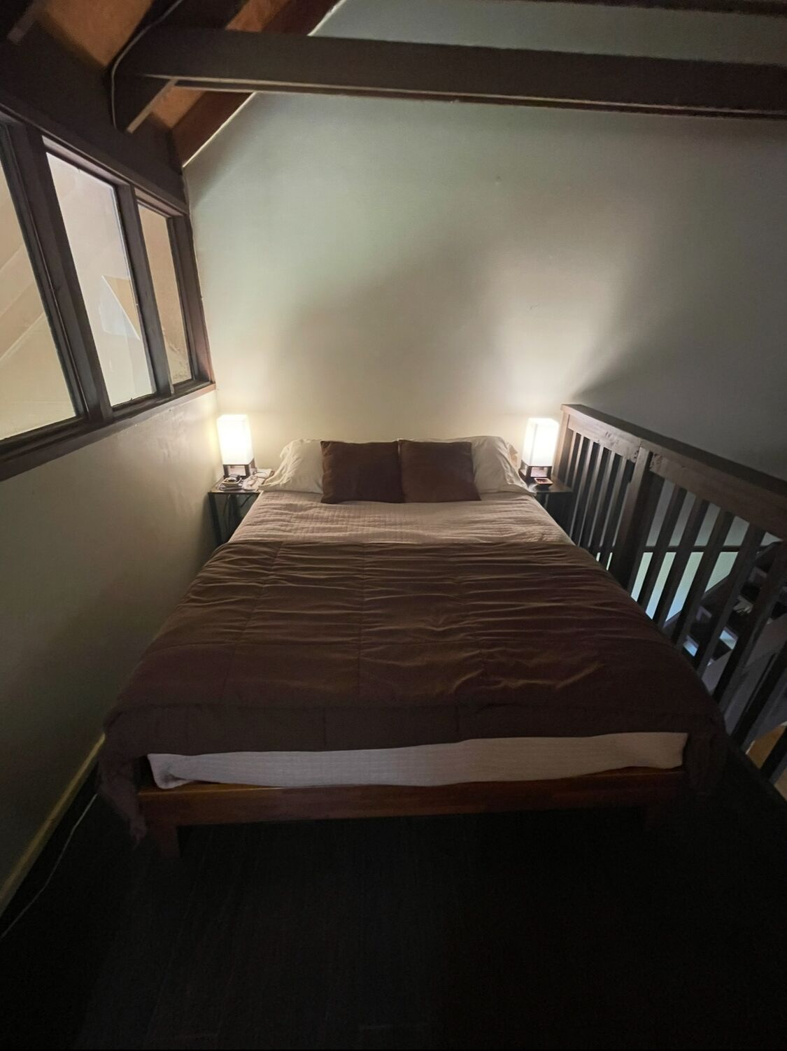 A bedroom with a bed, two bedside lamps, and a window.