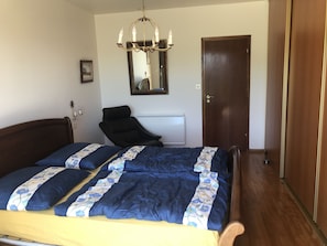 Une chambre à coucher avec un lit, une chaise, un lustre, une porte et un miroir.