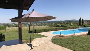 Un espace piscine offrant une vue dégagée sur le paysage environnant, un coin salon abrité et un chemin en pierre.