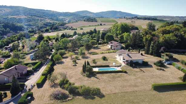 Un quartier résidentiel avec des maisons, une piscine et un paysage vallonné en arrière-plan.