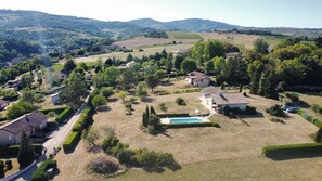 Un quartier résidentiel avec des maisons, une piscine et un paysage vallonné en arrière-plan.