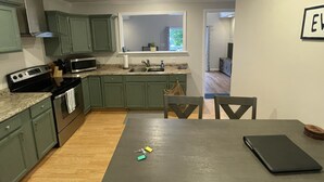 A compact kitchen with green cabinets, a built-in oven, and a window above the sink. - Lake Front Chalet (Queensbury)