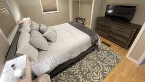 A bedroom with a bed, a wardrobe, a TV, and a window with blinds. - Lake Front Chalet (Queensbury)