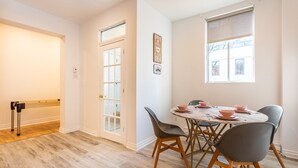 Een eethoek met een ronde tafel, vier stoelen en roze kommen.