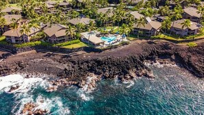 An aerial view of a resort with multiple buildings, a swimming pool, and a rocky coastline. - High-End Oceanfront Sanctuary with Upgraded Luxury Interior (Kailua Kona)