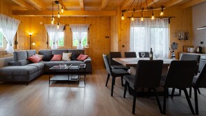 A cozy cabin interior with a sofa, dining table, chairs, and wooden floors. - Holiday Home Butkovic - Three Bedroom Holiday Home (Sunger)