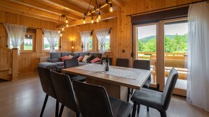 A wooden interior with a dining table, chairs, a sofa, and curtains. - Holiday Home Butkovic - Three Bedroom Holiday Home (Sunger)