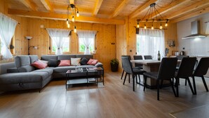 A cozy cabin interior with a sofa, dining table, chairs, and a kitchen area. - Holiday Home Butkovic - Three Bedroom Holiday Home (Sunger)