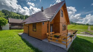 A wooden cabin with a sloped roof, a porch with benches, and a gravel driveway. - Holiday Home Butkovic - Three Bedroom Holiday Home (Sunger)