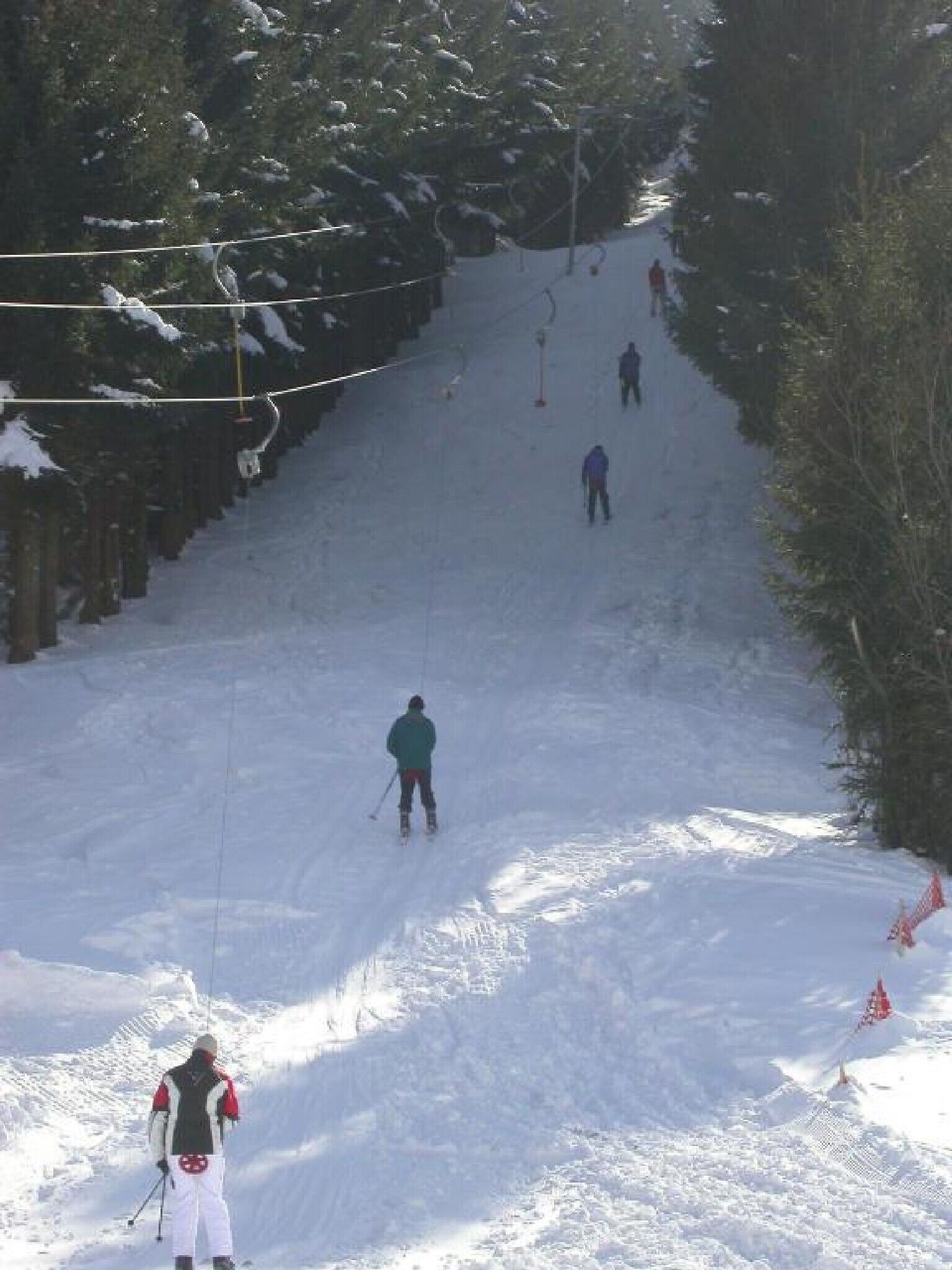 A snowy ski slope with skiers descending.