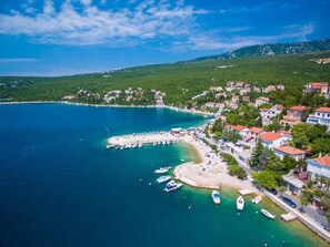 Vue aérienne d’une ville côtière avec un port de plaisance, des maisons et une plage.
