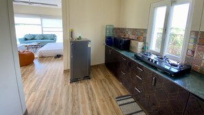 A modern kitchen with a built-in stove, a water dispenser, and a refrigerator. - GoBravo 71: 2Bhk Farm with Pool & Garden Sector 150 Noida (Noida)