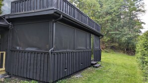 Un edificio de madera negra con ventanas grandes y un pequeño porche.