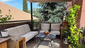 Een terras met een witte bank, een kleine tafel en een vloer met een patroon.