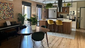 Een moderne keuken met houten balken, een eethoek met een houten tafel en stoelen, en een keukeneiland met barkrukken.