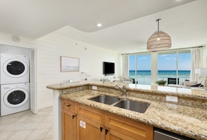 A modern kitchen with granite countertops, a double sink, and a built-in washer-dryer unit. - Aqua 2004 - Gulf-Front Escape, Beach Chairs, Sleeps 8 (Panama City Beach)