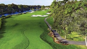 Ein Golfplatz mit einem Wasserhindernis, Wegen und Bäumen.