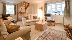 Ein gemütliches Wohnzimmer mit Treppe, zwei Sofas, einem Couchtisch und einer Lampe.