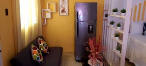 A compact living space with a sofa, a refrigerator, and a shelving unit with plants. - PV9/  Pine Villa is located in PortAntonio, -5 minutes  from the town center  .! (Port Antonio)