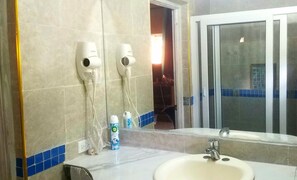 A bathroom with a sink, two hair dryers mounted on the wall, and a mirror reflecting a window. - PV9/  Pine Villa is located in PortAntonio, -5 minutes  from the town center  .! (Port Antonio)