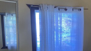 A bathroom with a mirror, a shower curtain, and a ceiling-mounted air conditioning unit. - Ocean front. Kiters hotel (Buen Hombre)