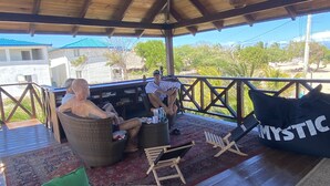 A covered outdoor seating area with wicker furniture, a red cushion, and a black bean bag labeled "MYSTIC". - Ocean front. Kiters hotel (Buen Hombre)
