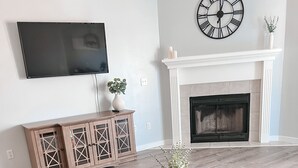 Un salon avec une cheminée, un téléviseur, un meuble en bois et une table basse ronde.