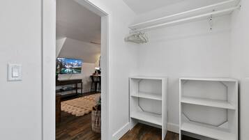 A room with a white closet, a television, and a wooden floor.