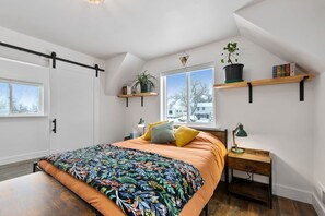 A bedroom with a bed, a nightstand, a desk, a window, and a plant. - Bright, colorful & cozy studio in oldtown Timnath. Walking distance to a brewery (Timnath)