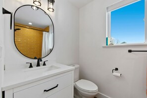 A bathroom with a white sink, black faucet, and a round mirror. - Bright, colorful & cozy studio in oldtown Timnath. Walking distance to a brewery (Timnath)