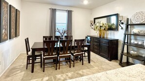 A dining area with a table and chairs, a cabinet, and a decorative shelf.