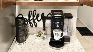 A kitchen counter with a coffee maker, a coffee grinder, and a coffee mug.