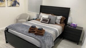 A neatly made bed with a grey and white patterned bedspread, two brown towels, and a black headboard. - PickleballShopsFoodies 5Bedrms 2Washers 3Dryers (Montclair)