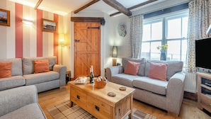 A cozy living room with two grey sofas, wooden coffee table, and a large window with curtains. - Nobles Cottage - UK43351 (Whitby)