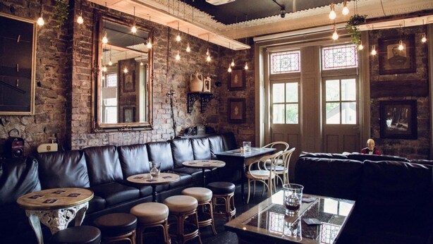 Un restaurant chaleureux avec un mur en briques, des sièges en cuir et des luminaires suspendus.