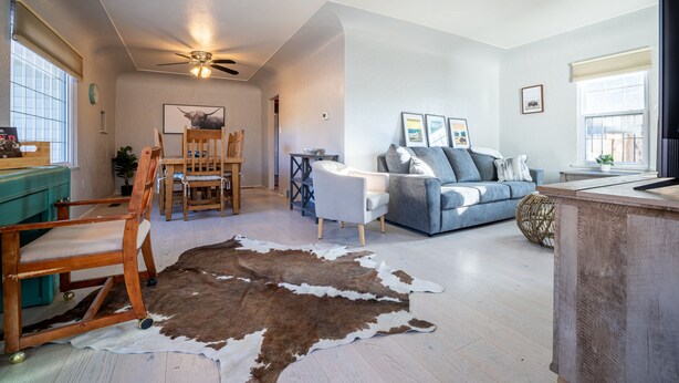 A spacious living room with a dining area, a ceiling fan, and a large window providing natural light. - Charming Cody Home - sleeps 5, walking distance to downtown! (Cody)