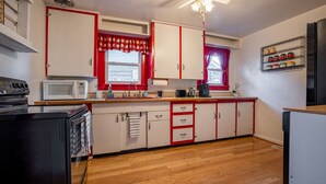 A compact kitchen with white cabinets, a microwave, a stove, and a refrigerator. - Charming Cody Home - sleeps 5, walking distance to downtown! (Cody)