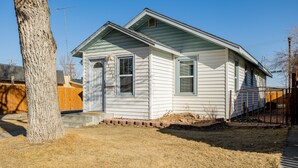 A single-story house with a front porch, a small front yard, and a wooden fence. - Charming Cody Home - sleeps 5, walking distance to downtown! (Cody)