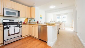 A modern kitchen with wooden cabinets, stainless steel appliances, and a central island. - Luxury condo near Irvine Business & UCI Hospital (Irvine)
