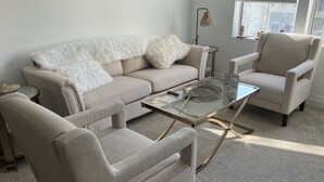 A living room with a beige sofa, two armchairs, a glass coffee table, and a small side table. - Luxury condo near Irvine Business & UCI Hospital (Irvine)