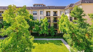 A row of townhouses with balconies, a central lawn, and surrounding trees. - Luxury condo near Irvine Business & UCI Hospital (Irvine)